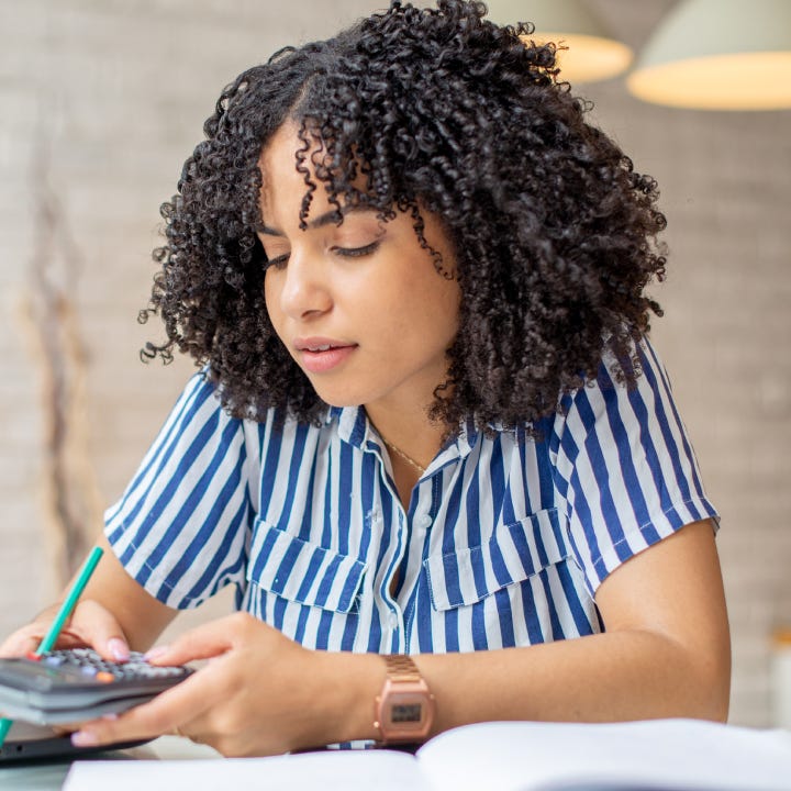 Woman using calculator and working on laptop